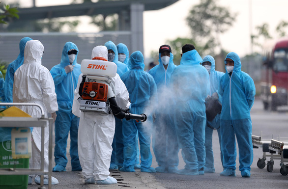A health worker sprays disinfectant on entrants into Vietnam. Photo: Viet Dung / Tuoi Tre